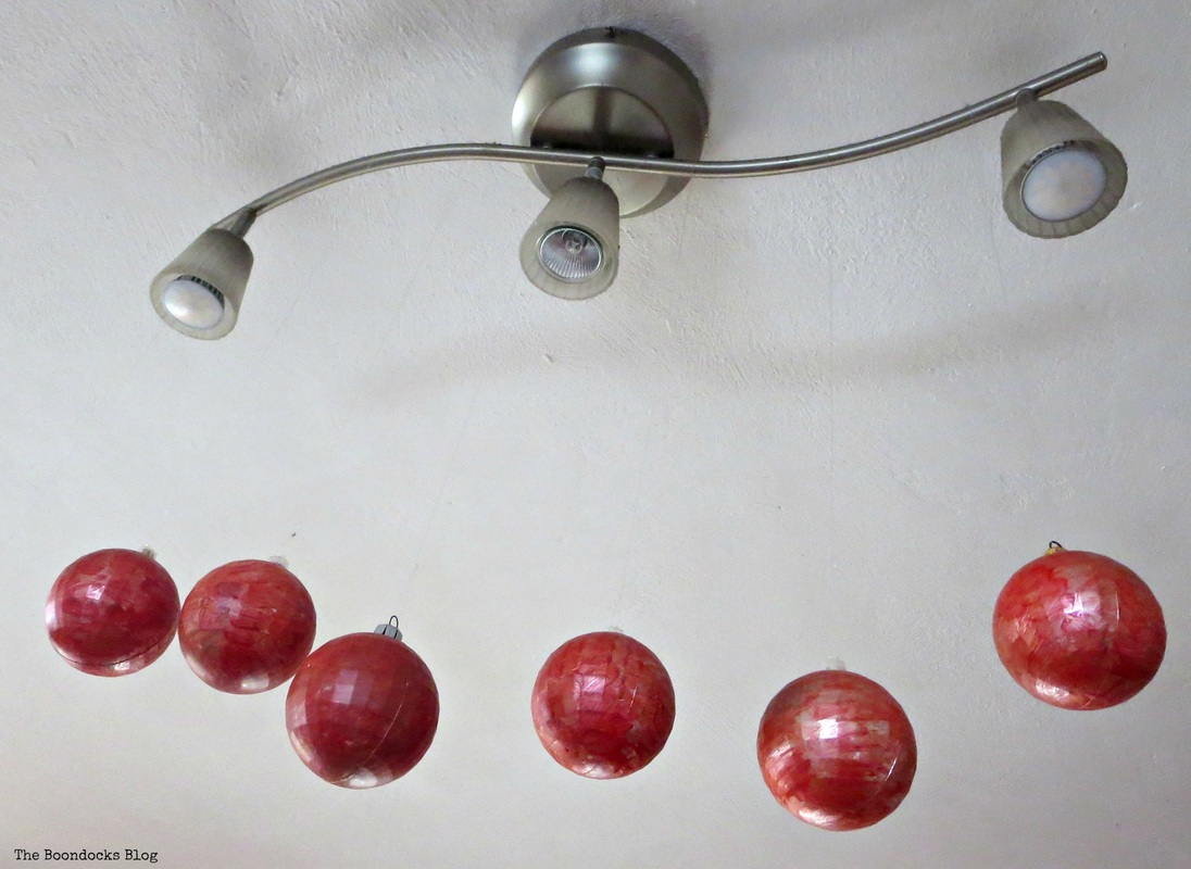 Red baubles hanging from spotlights The Inspiration for my Christmas tree - the Boondocks blog