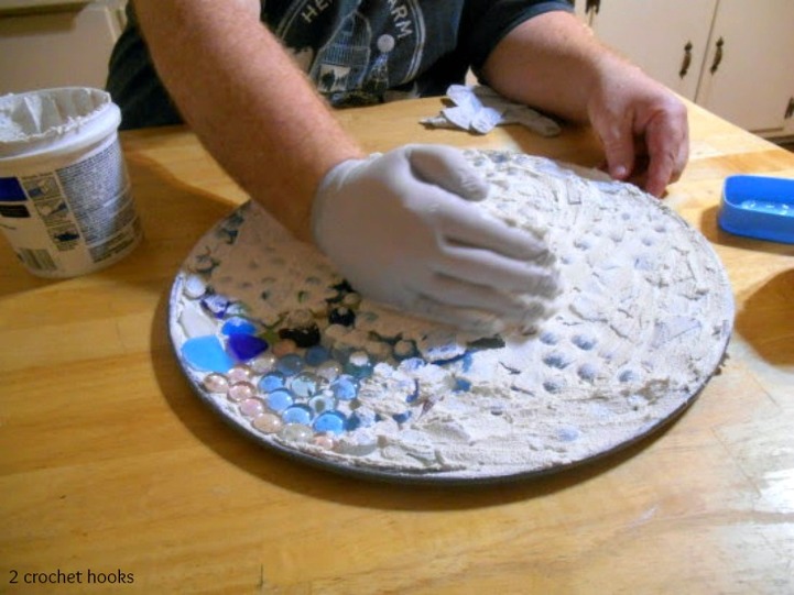 spreading grout on sea glass and marbles.