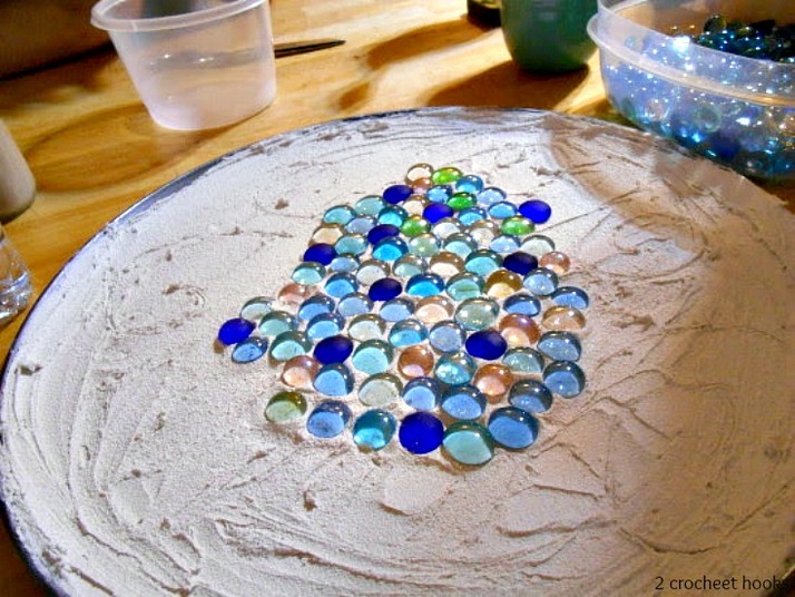 Adding marbles on the grout topped pizza pan.