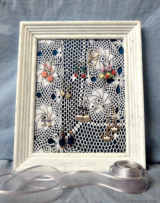 Earring organizer made with a frame, a blue satin blouse and a doily. 