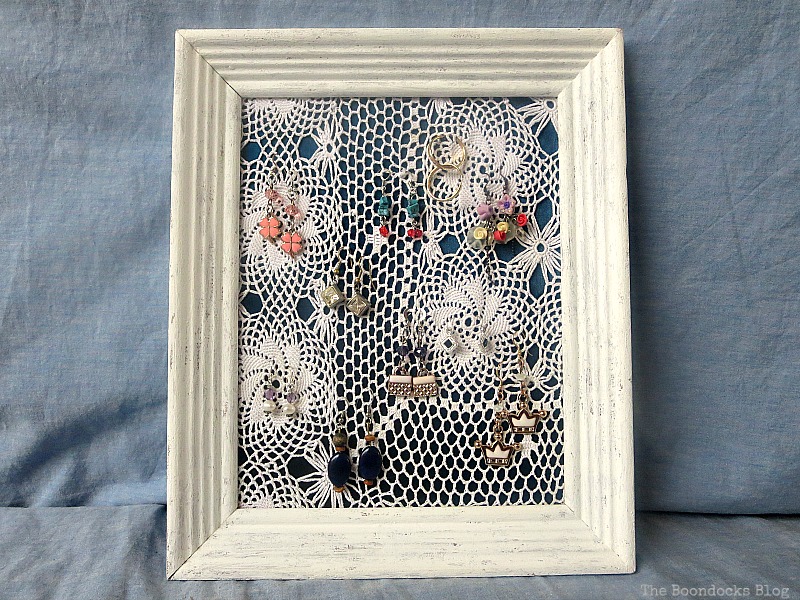 The finished earring organizer made with a frame, a blue satin blouse and a doily. 