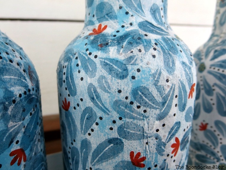Bottle decoupaged with blue paint showing through.
