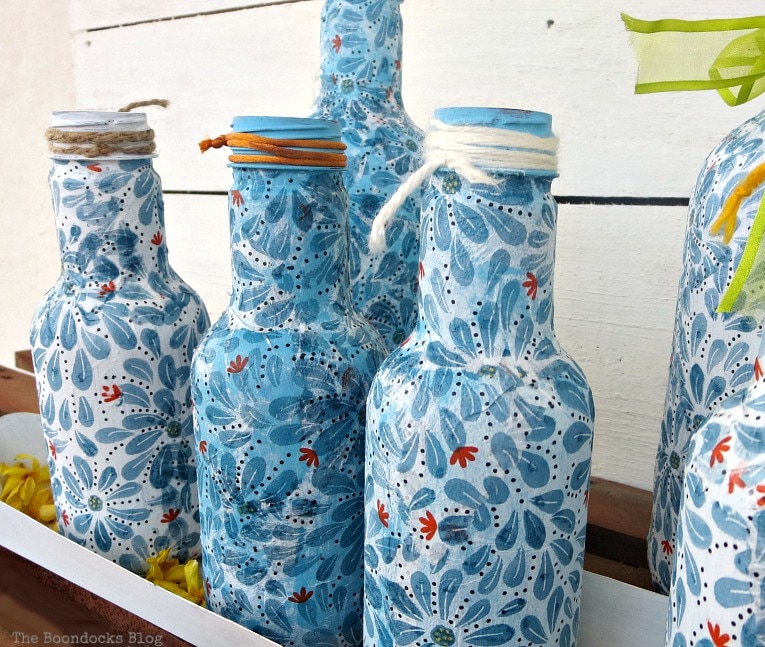 Finished Decoupaged bottles set in achicken feeder.