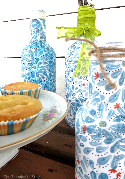 Three plastic bottles covered with pretty napkin paper using decoupage.