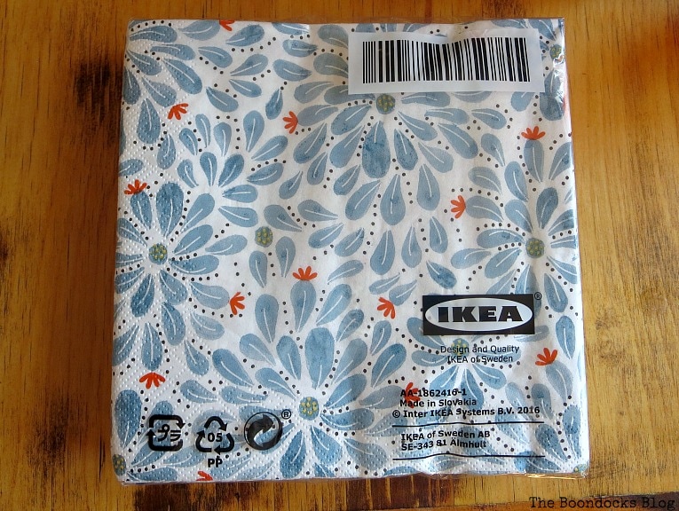 Ikea paper napkins with blue flowers in package on a wooden table surface.