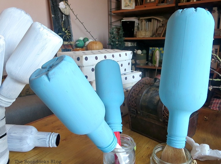 Upside down plastic bottles drying from being painted with blue chalk paint.