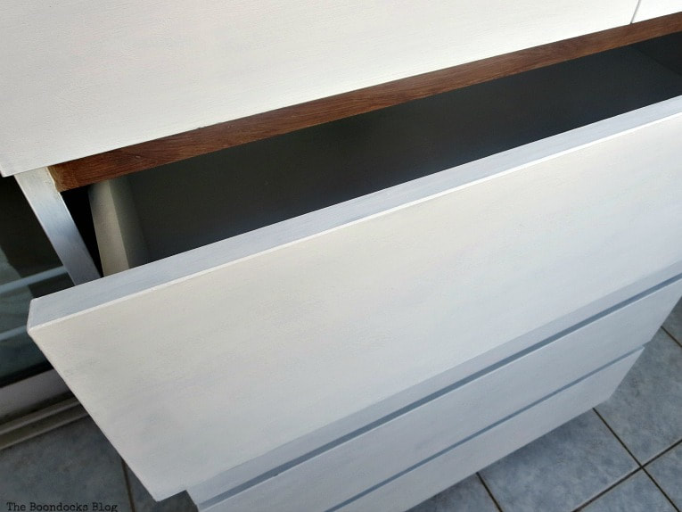 The front of the dresser painted white, with the top drawer partially opened.