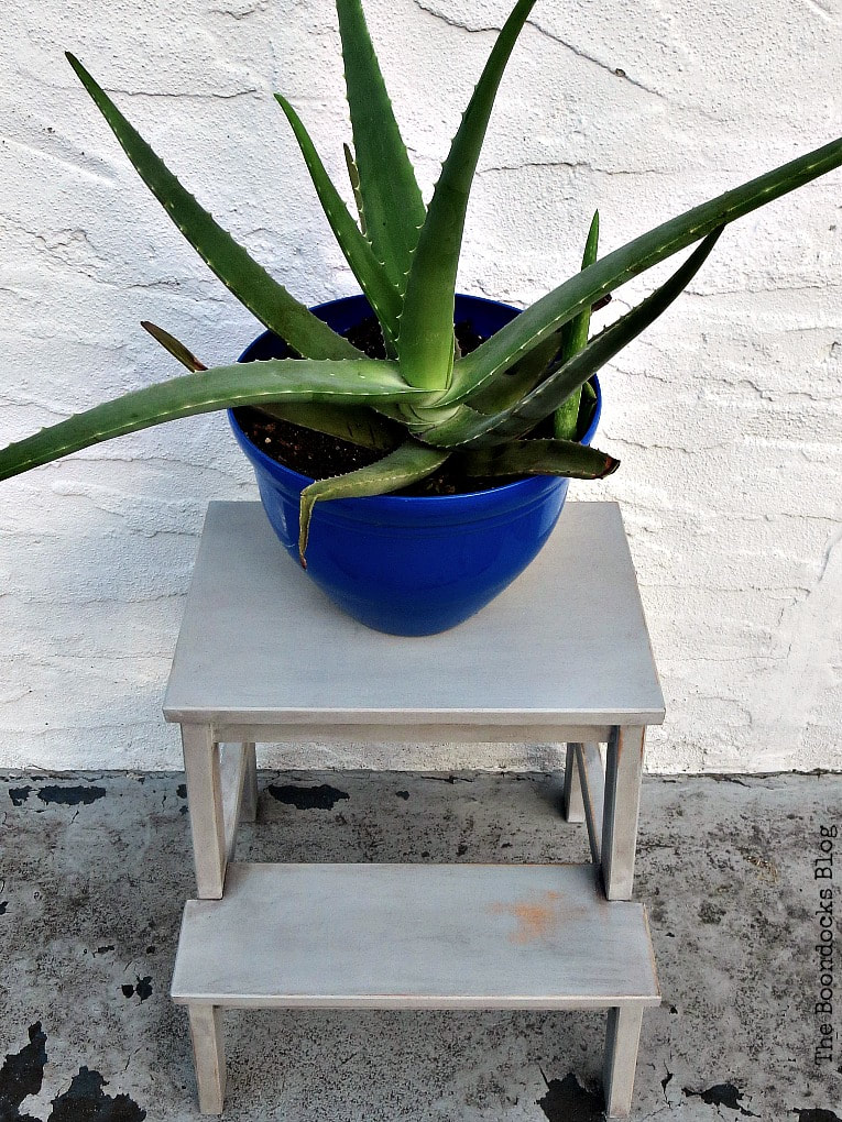 A blue planter filled with an aloe plant on top of a painted Ikea Bekvam step stool.