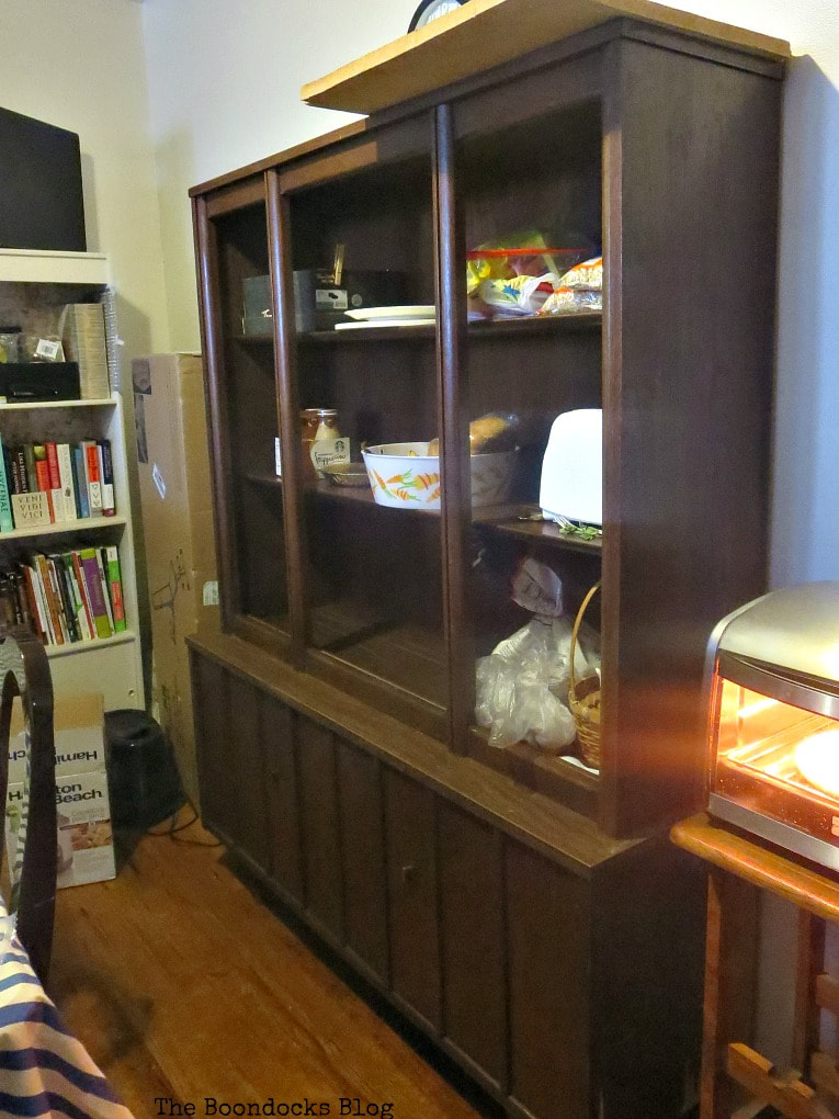 Showing the before picture of the China cabinet with glass doors and open shelves.