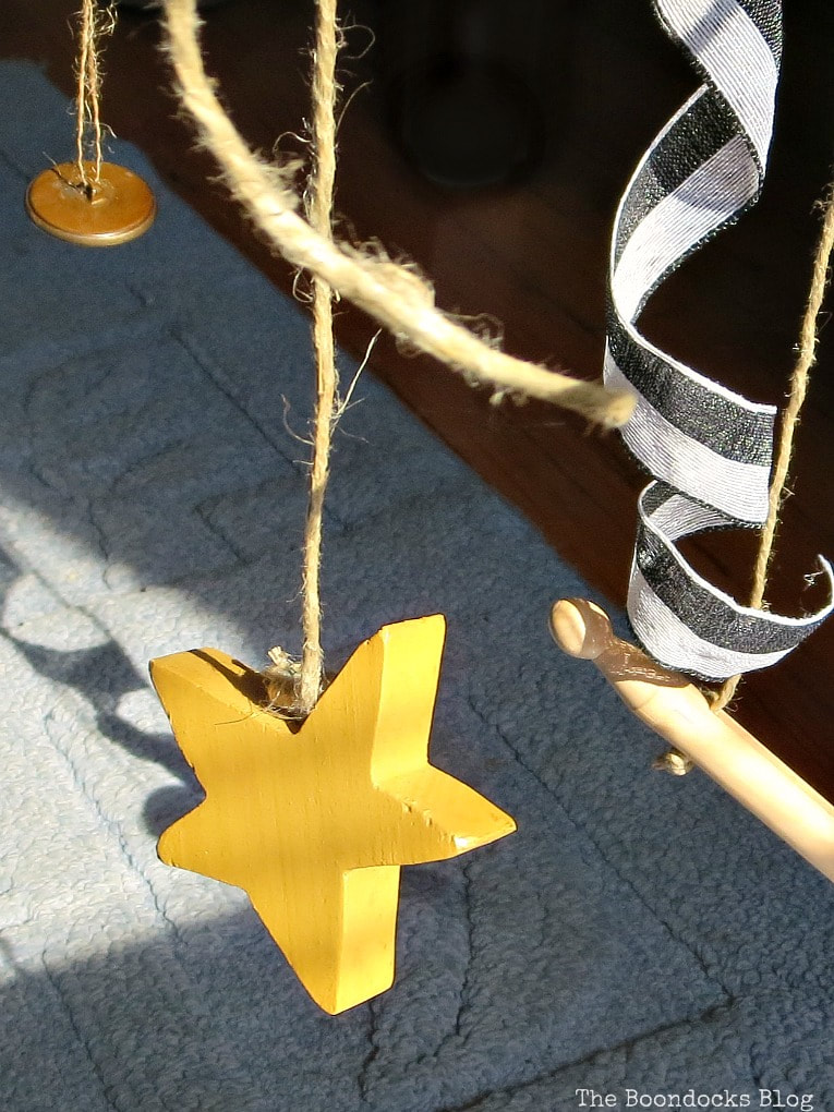 Close up of hanging wooden star, twine, buttons, wooden peg and ribbon.