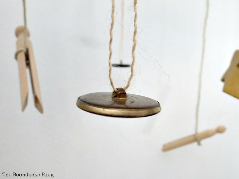 Close up of gold button hanging with twine and wooden pegs hanging with twine.