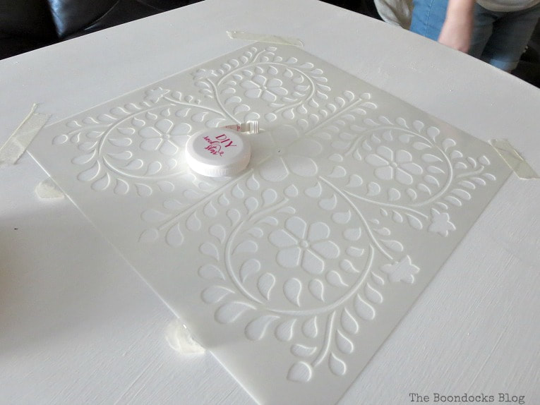 Positioning stencil on table which has been painted white, How to Give your Old Table a New Look with Stencils, the boondocksblog.com