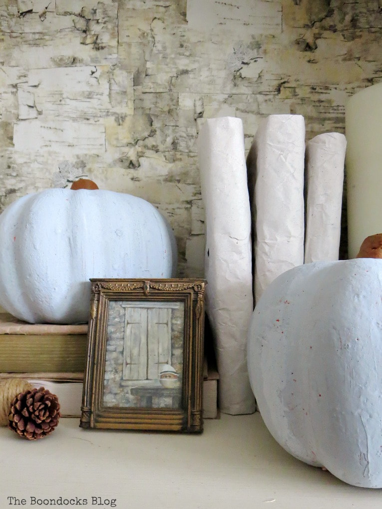 Fall vignette with blue vase, books, pine cones, pumpkins, art and a candle, #falldecor #fallvignette #bookcasestyling #pumpkins #pinecones #upcycled How to Style a Bookcase for Fall 3 Different Ways www.theboondocksblog.com