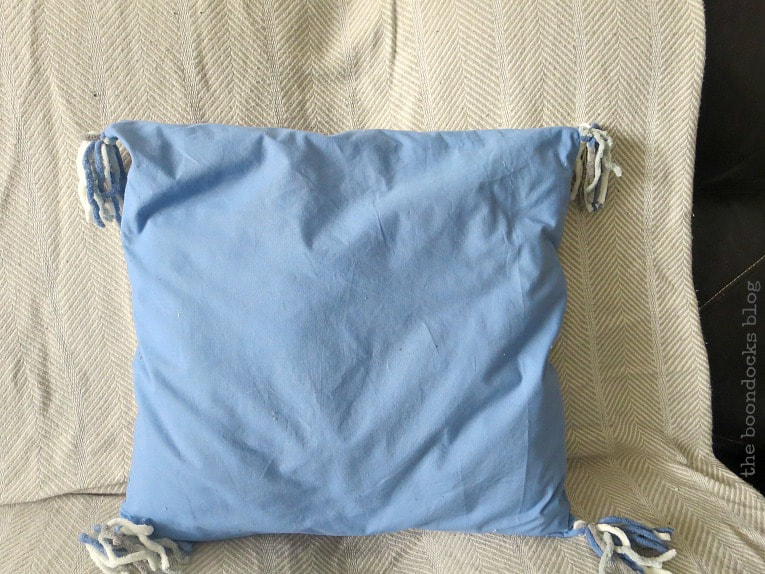 pillow made from blue sheet with yarn tassels, How to Make Easy Pillows out of Fabric Remnants 5 ways www.theboondocksblog.com