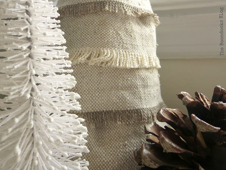 Closeup of a white Christmas tree, fabric Christmas tree and a pinecone.