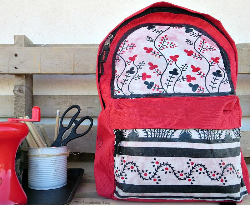 Red backpack next to school supplies.