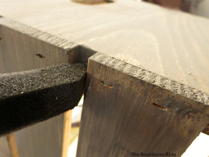 Close up image of applying barnwood stain in between the slats of the wooden crate.