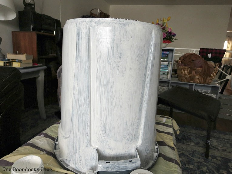 Painting bottom of bucket with white paint.