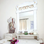 Painted white wood mirror over a white painted dresser.