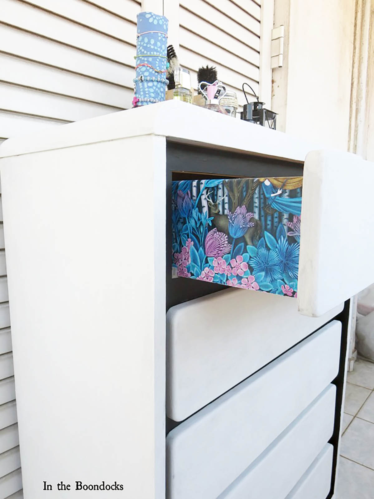 A side view of the DIY dresser makeover featuring blue and pink floral gift wrap decoupaged on the sides of the drawers.